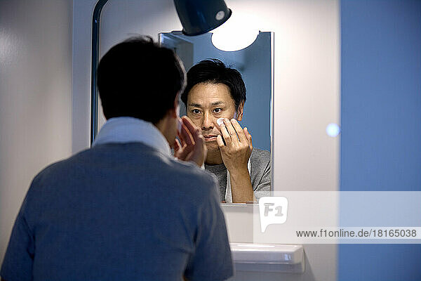 Japanischer Mann trägt Gesichtscreme auf