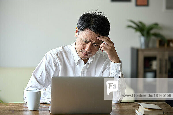Japanischer Mann mit Laptop zu Hause