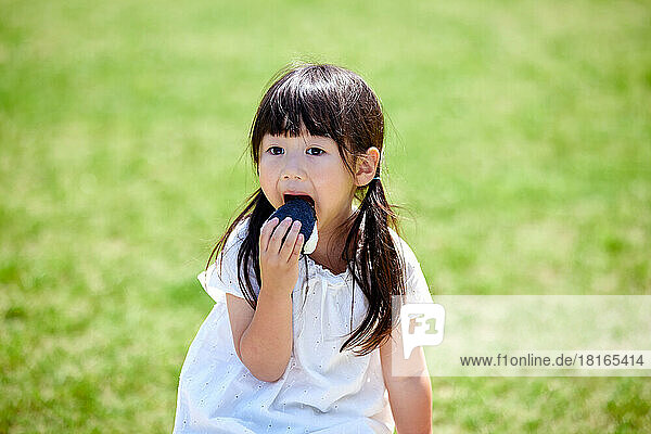 Japanisches Kind beim Essen in einem Stadtpark