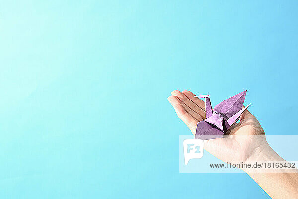 Frau hält Origami-Papierkranich