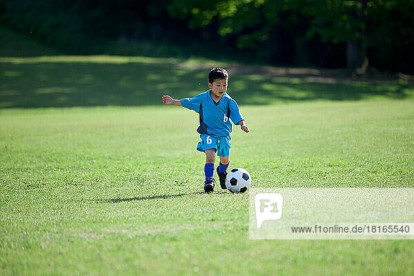 Japanese kid playing soccer at a city park