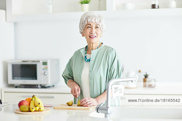 Japanische Seniorin beim Schneiden einer Kiwifrucht