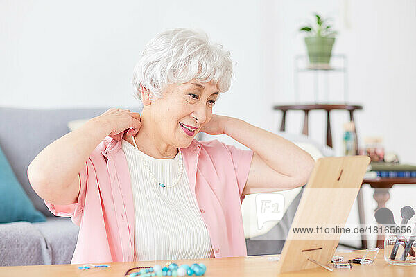 Japanische ältere Frau legt Halskette an
