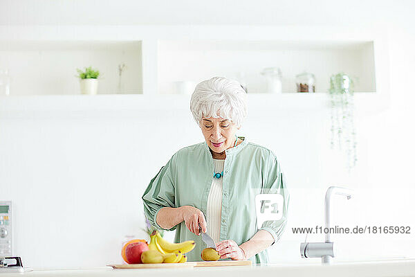 Japanische Seniorin beim Schneiden einer Kiwifrucht