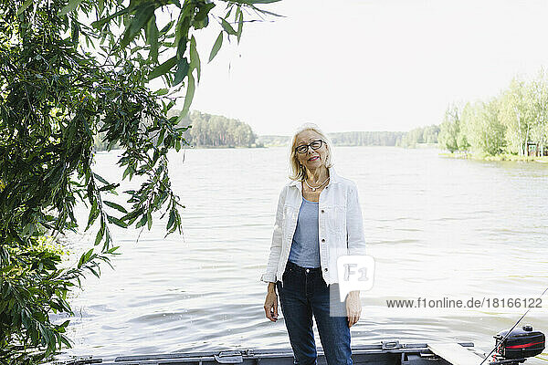 Senior woman standing in motorboat on lake