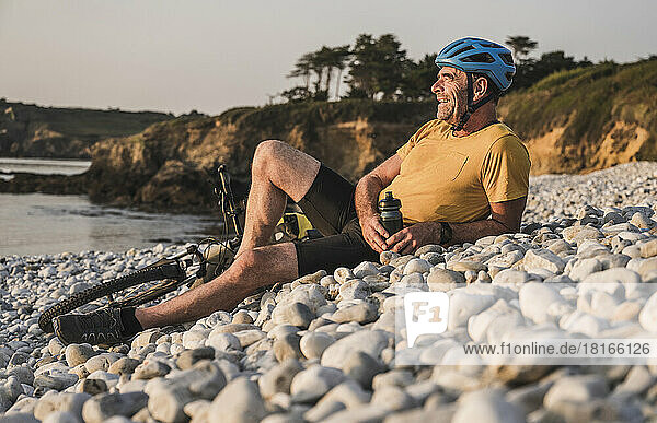 Happy man wearing helmet relaxing at beach