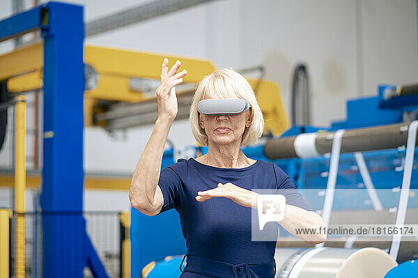 Senior businesswoman with futuristic glasses gesturing in industry