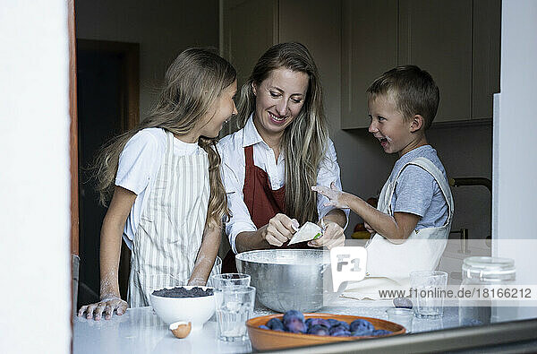 Cheerful children helping mother cooking at home