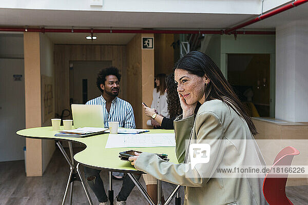 Smiling businesswoman sitting at table in office