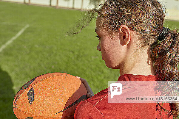 Girl holding rugby ball on sunny day