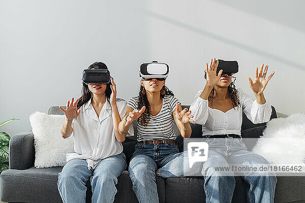 Multiracial friends with futuristic glasses gesturing in living room