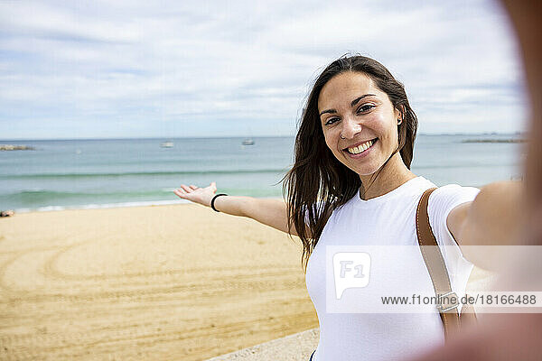 Happy woman taking selfie at beach