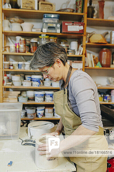Reifer Töpfer mit Keramik arbeitet in der Werkstatt