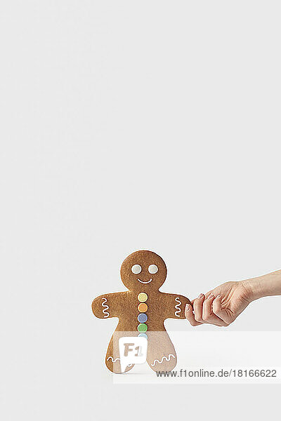 Hand of woman holding freshly backed gingerbread cookie against white background