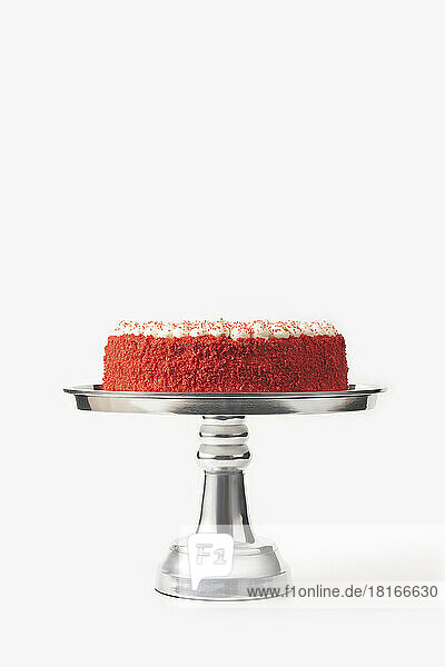 Delicious homemade red velvet cake on silver cakestand against white background