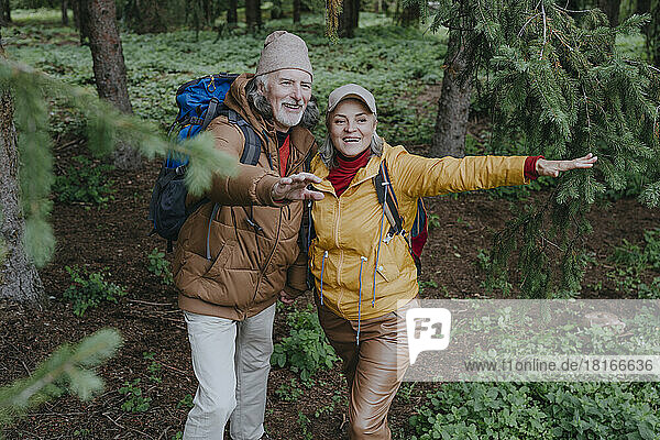 Happy heterosexual couple gesturing in forest