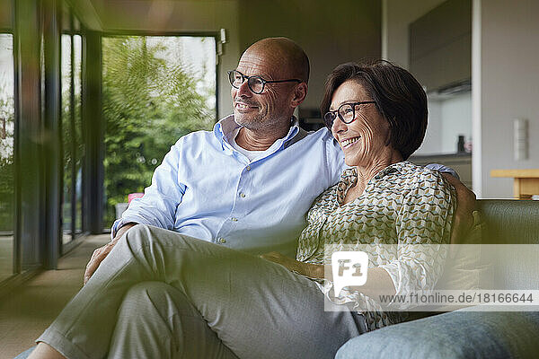 Happy senior man and woman sitting on sofa at home