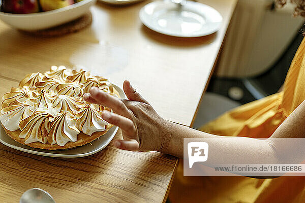 Hand of girl touching meringue pie on table