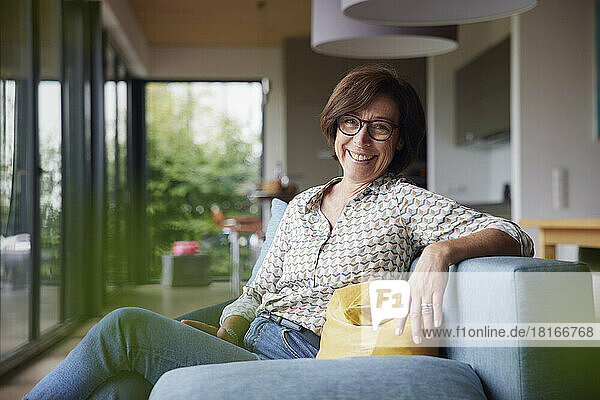 Happy senior woman sitting on sofa at home