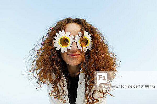 Smiling woman with curly hair wearing sunflower sunglasses