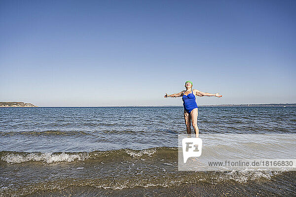 Woman with arms outstretched amidst sea enjoying sunshine