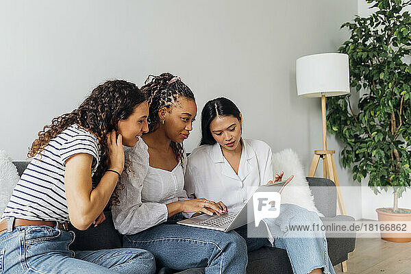 Woman doing online shopping on laptop with friends in living room