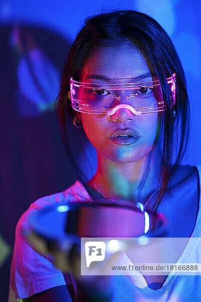 Young woman with smart glasses holding mirror