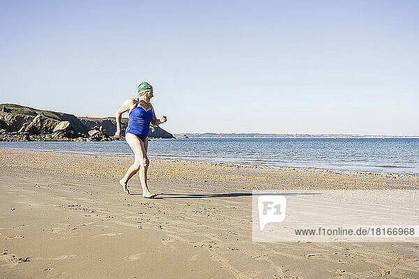 Frau im Badeanzug joggt am Strand