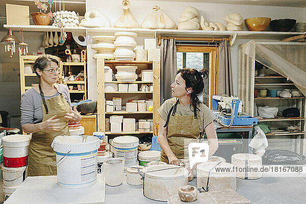 Potter talking to colleague working at ceramics workshop