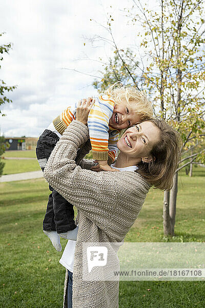 Cheerful woman playing with son at park
