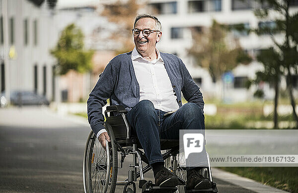 Happy senior man sitting on wheelchair in the city