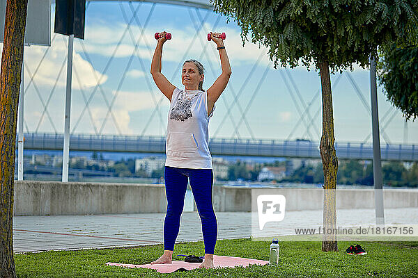 Mature woman exercising with weights in park