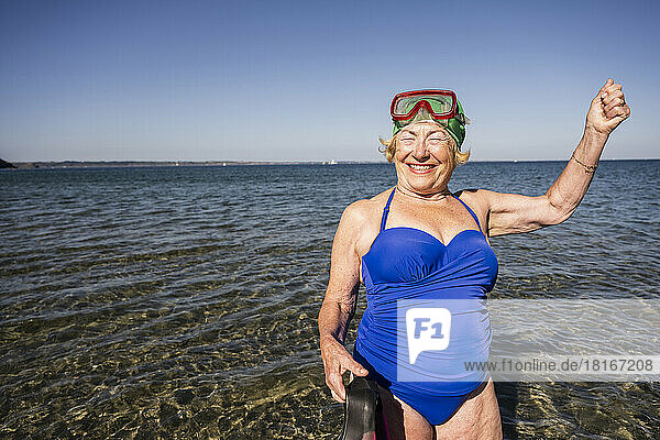 Cheerful woman with swimming goggles at beach