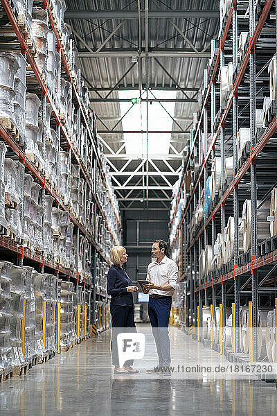 Senior businesswoman with colleague discussing in warehouse