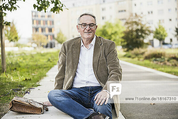 Smiling senior man wearing eyeglasses on concrete bench