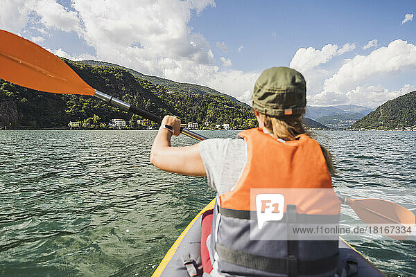 Woman wearing life jacket kayaking at lake