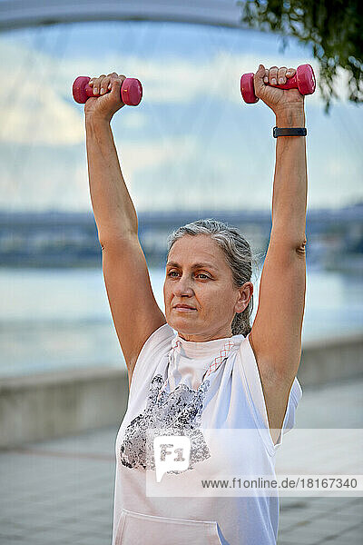 Mature woman lifting weights in park