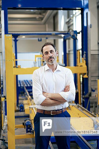 Mature businessman with arms crossed in industry