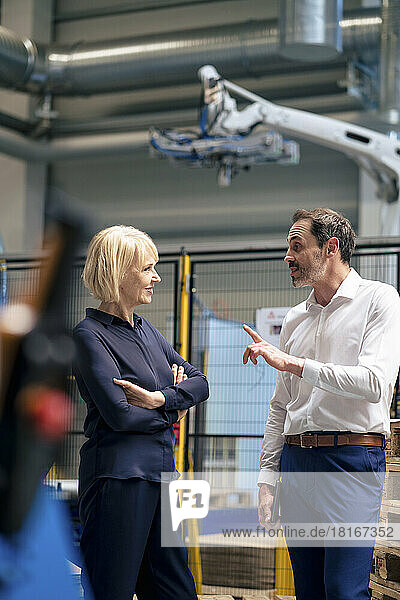 Businessman gesturing and talking with businesswoman in industry