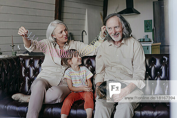 Großeltern und Enkelin spielen zu Hause buntes Plastikschnurspielzeug