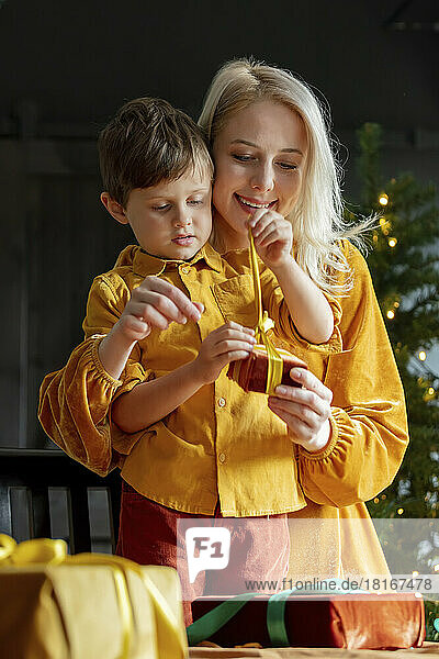 Mother showing son how to tie bow on present