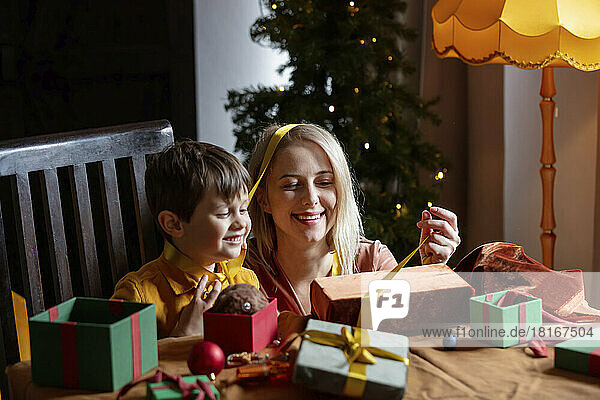 Happy mother and son wrapping gifts at home