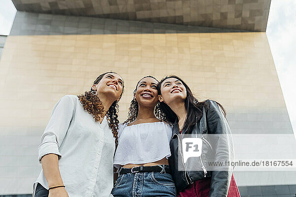 Lächelnde junge gemischtrassige Freunde vor der Wand
