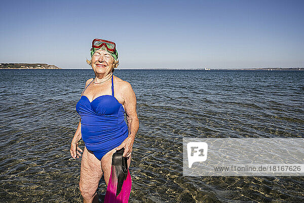 Smiling woman with diving flippers standing in sea