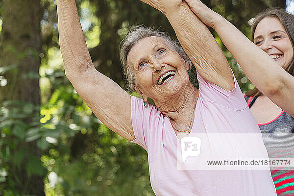 Happy fitness instructor guiding senior woman exercising at park