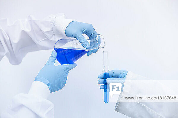 Scientist pouring blue liquid in test tube at laboratory