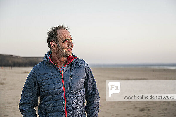 Contemplative mature man wearing jacket at beach