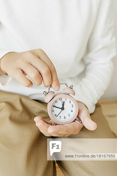 Hands of girl holding pink alarm clock