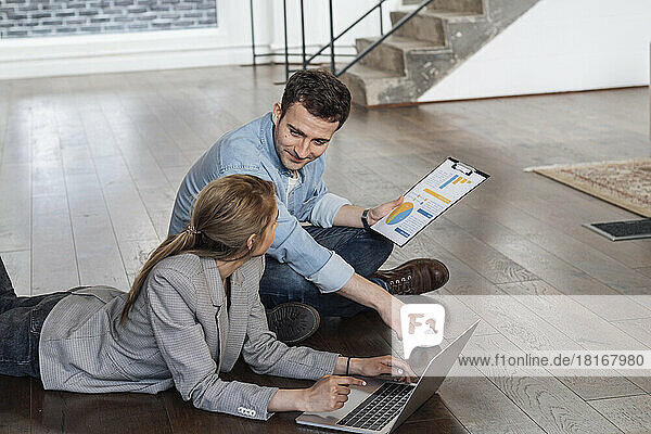 Businessman and woman working together in modern office sitting on floor