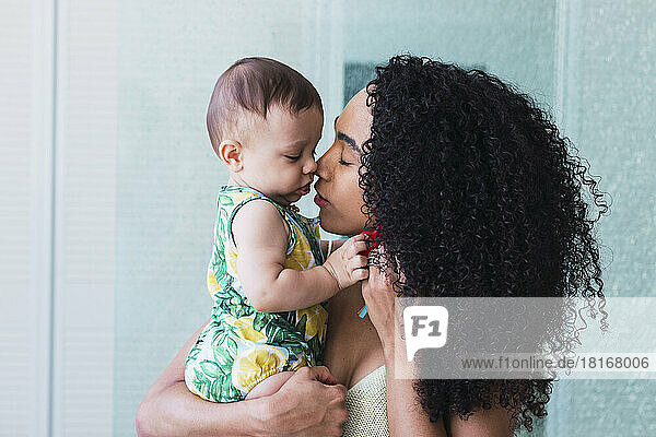 Woman with curly hair embracing cute toddler son at home